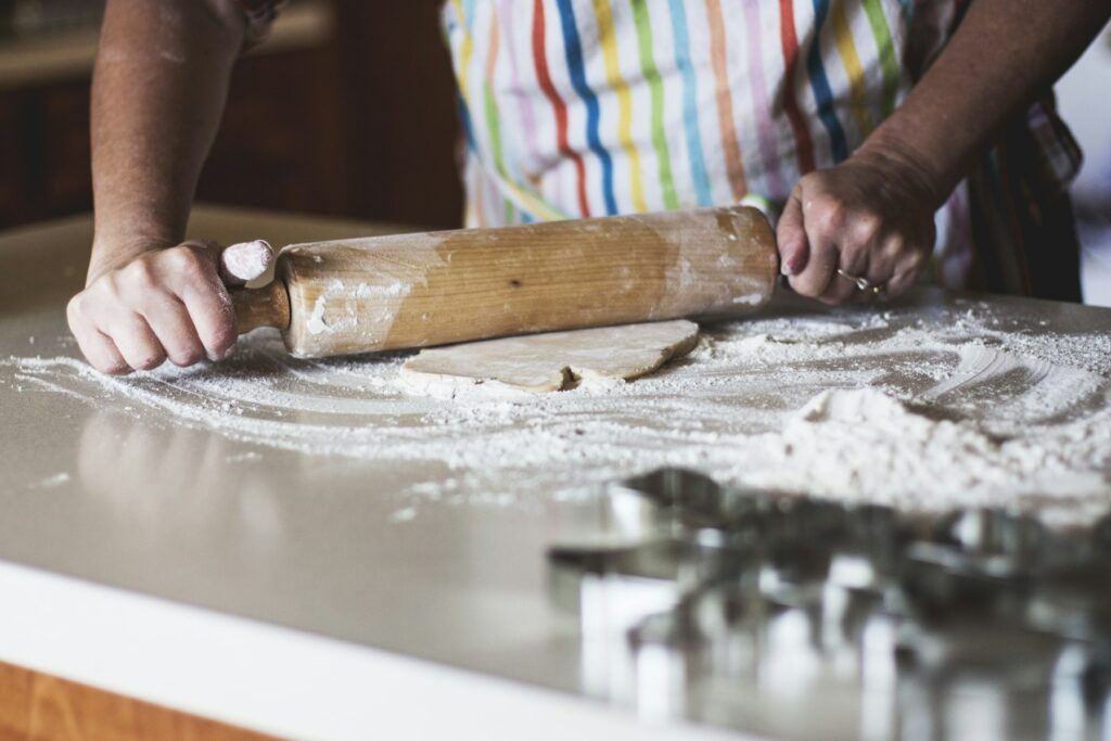 Home Home baker rolling out dough with a wooden rolling pin and cookie cutters