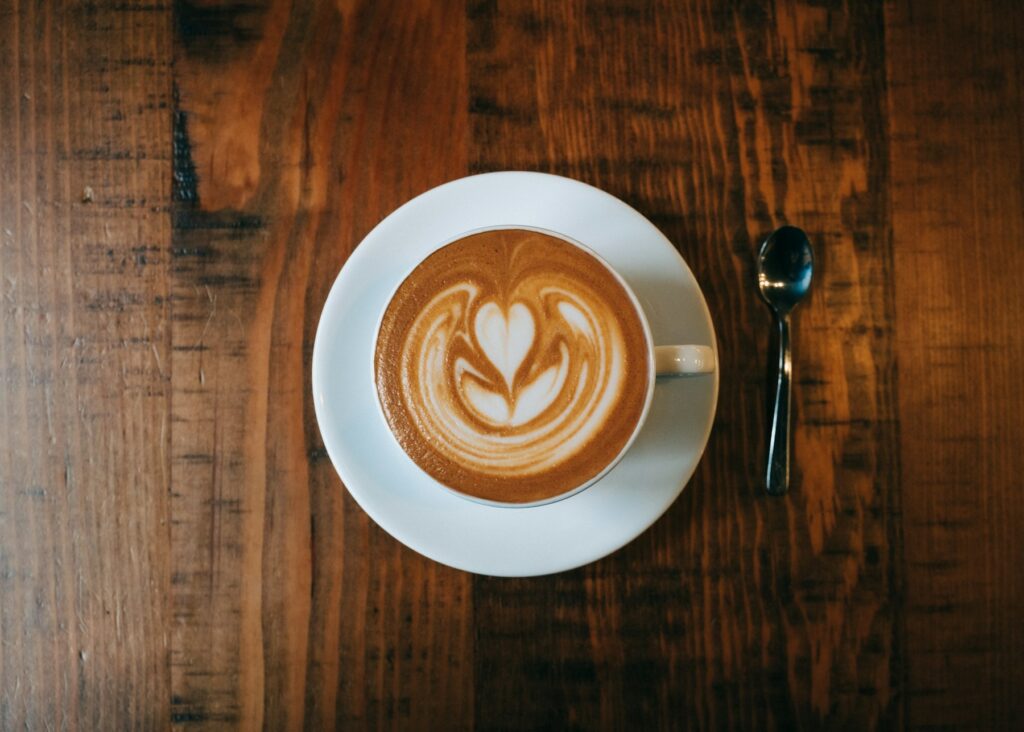 Home Latte with leaf latte art in a white cup on a wooden table