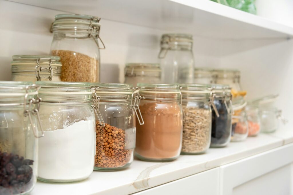 Home Pantry shelf with glass jars of flour, grains and spices