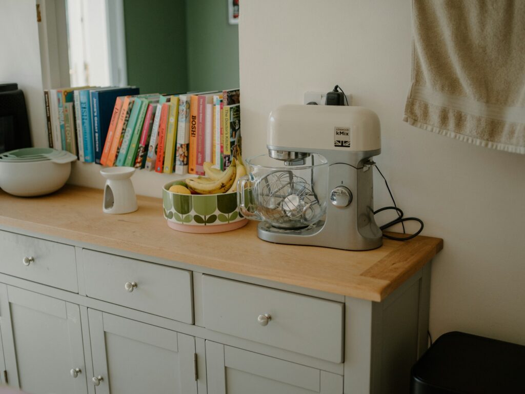 Home Stand mixer on a kitchen counter beside cookbooks and a fruit bowl
