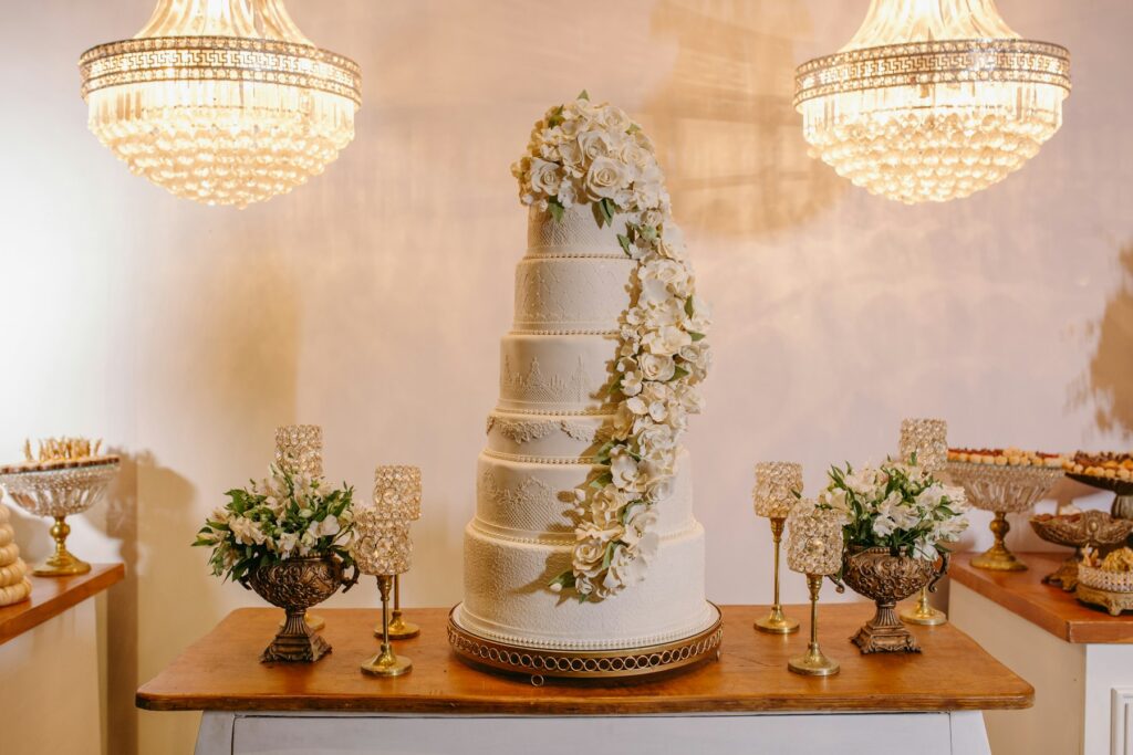 Home Tiered white wedding cake decorated with flowers on a reception table